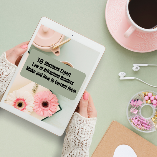 Person holding a tablet with a screen displaying text about mistakes in attraction readers, surrounded by a cup of coffee, flowers, and stationery on a light green background that represents a digital guide titled " 18 mistakes expert law of attraction readers make and how to correct them " and you can buy it at www.laiamunozauthor.com