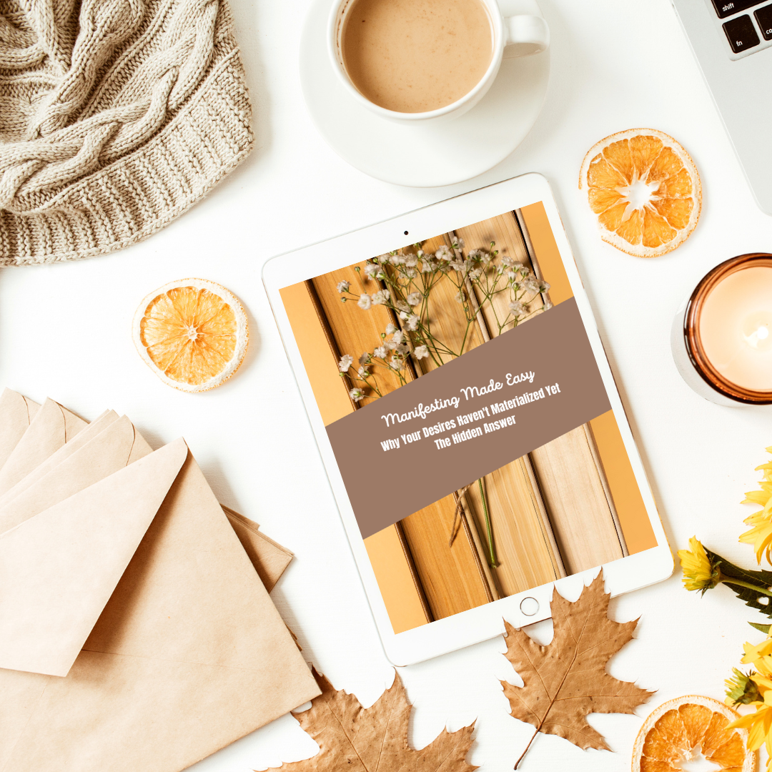 Tablet displaying a book cover on a desk with coffee, oranges, and a candle with the ebook titled " manifesting made easy. why your desires have not yet materialized. the hidden answer " and you can get it at laiamunoauthor.com