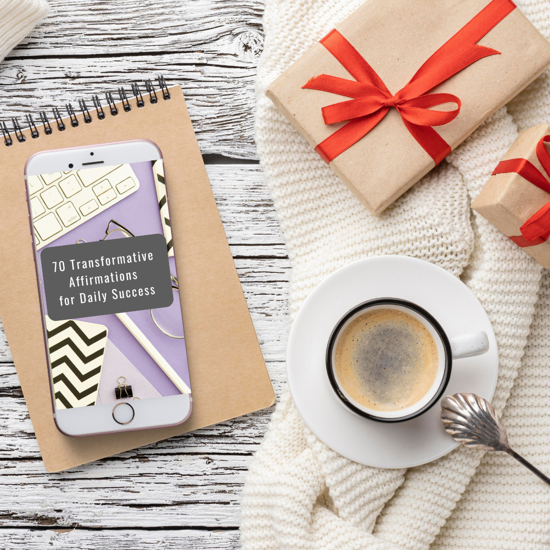 Phone with app on screen, notebook, coffee cup, and wrapped gifts on a textured surface that features an ebook titled " 70 transformative affirmations for daily success "