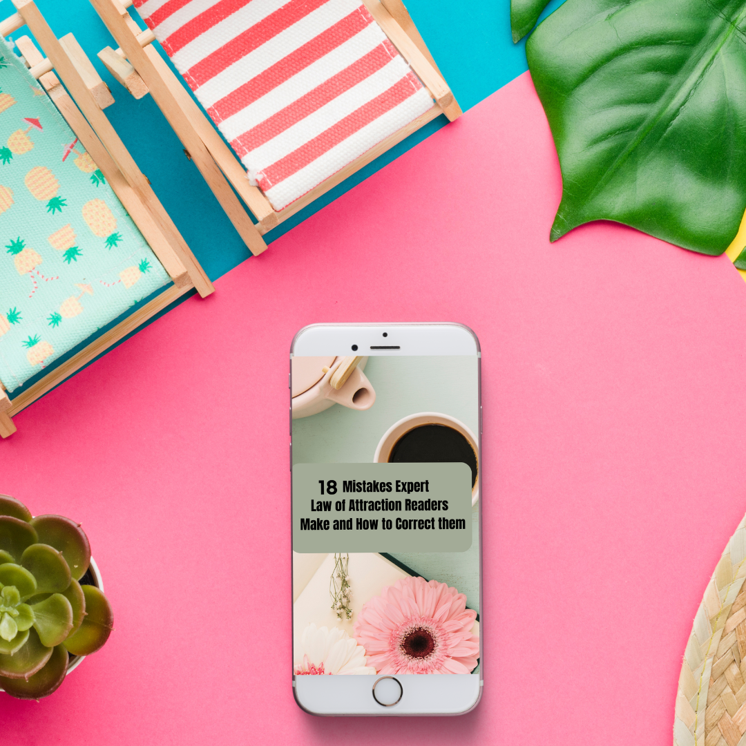 Phone displaying a book cover with text on a pink surface with decorative items that represent a digital book titled " 18 mistakes expert law of attraction readers make "